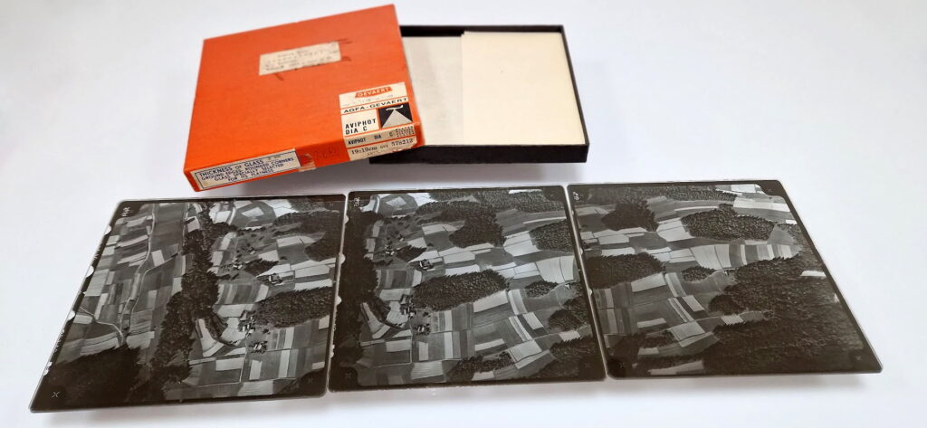 Ilustracja przedstawia "paczkę" archiwalnych zdjęć lotniczeych wykonanych na płytach szklanych.