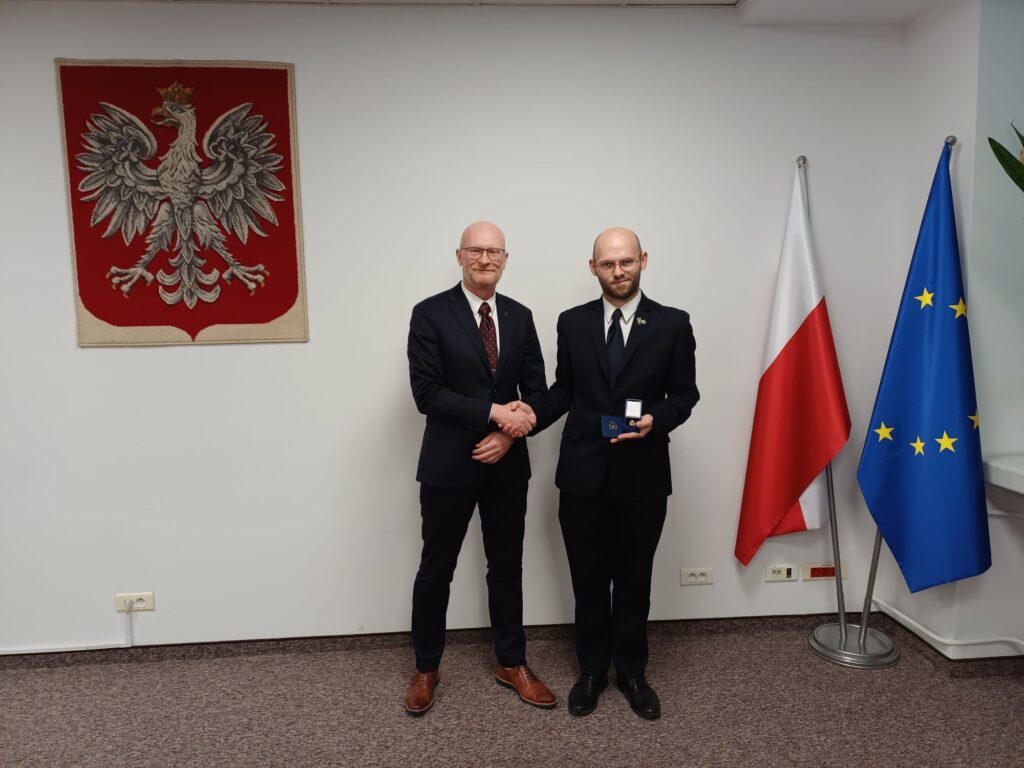 Główny Geodeta Kraju Andrzej Żylis wręcza odznakę Mariuszowi Meusowi