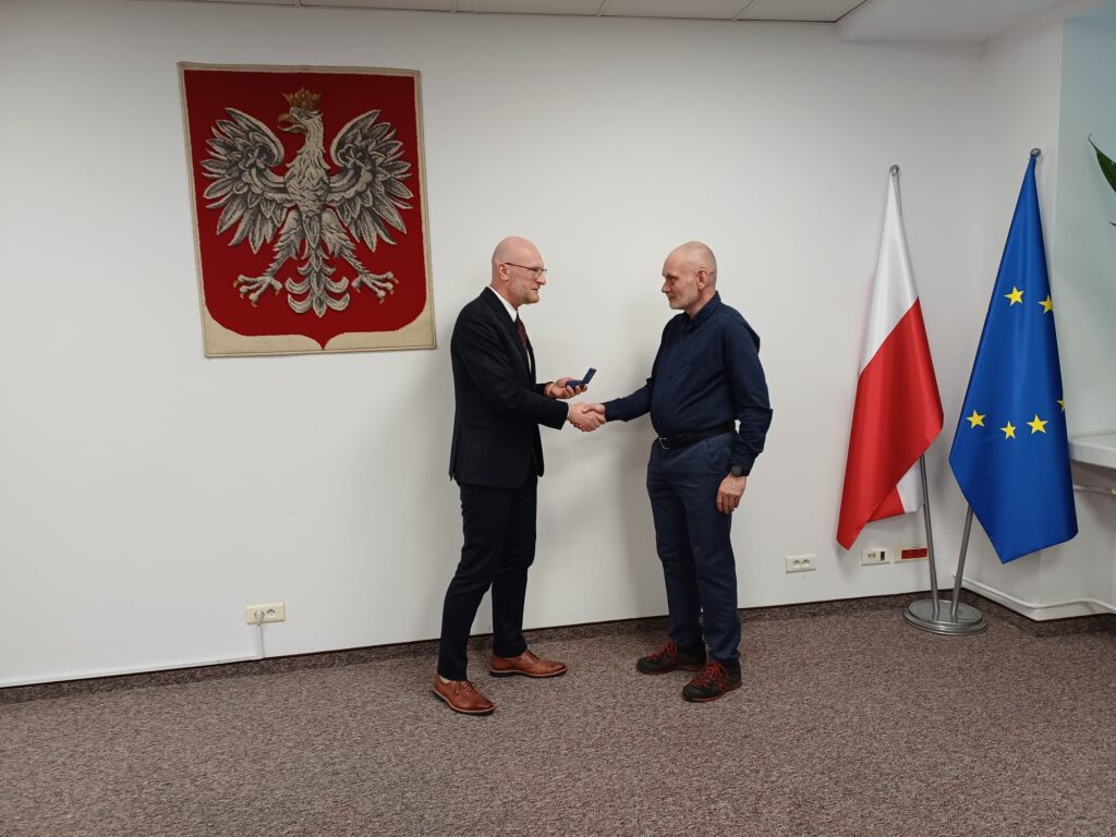 Główny Geodeta Kraju Andrzej Żylis wręcza odznakę Patrykowi Charydczakowi