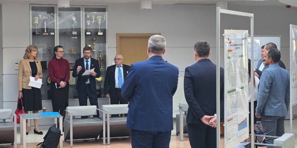 Fot. 1. Zdjęcie przedstawia hol w siedzibie GUGiK przy ul. Olbrachta 94B z osobami przystępującymi do egzaminu słuchającymi wyjaśnień członków Komisji Egzaminacyjnej.